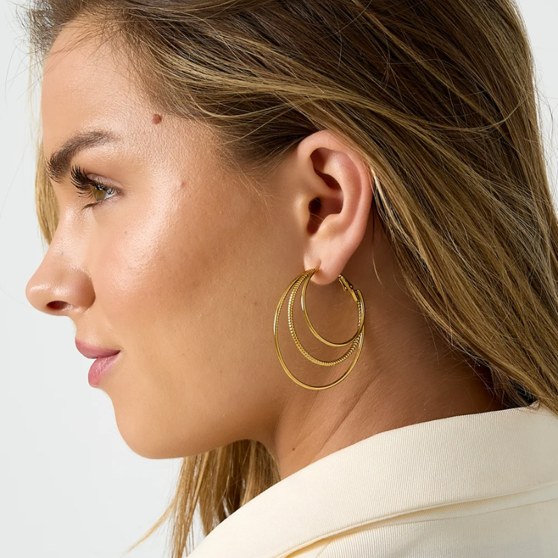 Créoles triple anneaux dorées portées vue d’ensemble style élégant et moderne