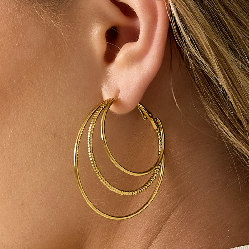 Créoles triple anneaux dorées en acier inoxydable portées de près effet multi anneaux tendance