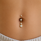 Photo portée d'un piercing nombril en acier chirurgical doré avec pendentif de trois oxydes de zirconium, barre 1,6 x 10 mm.