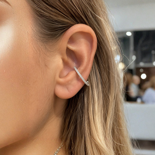 Piercing conch argenté serti de pierres brillantes, porté en diagonale sur l'oreille d'une femme.